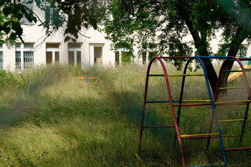 an old abandoned kindergarten building with an overgrown kindergarten garden