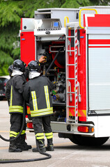 firefighters with uniforms and protective helmets and fire truck in action during emergency in city © ChiccoDodiFC