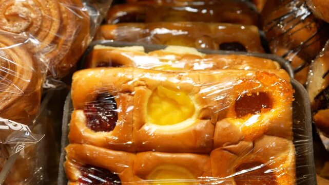 Close-up of a male customer's hand taking a set of buns with jam from a bakery counter
