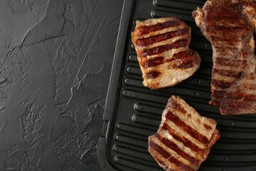 Delicious grilled beef meat on black textured table, top view. Space for text