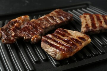 Delicious grilled beef meat on black table, closeup