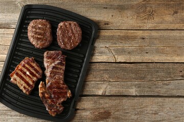 Delicious grilled beef meat on wooden table, top view. Space for text