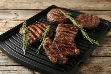 Delicious grilled beef meat with rosemary on wooden table, closeup