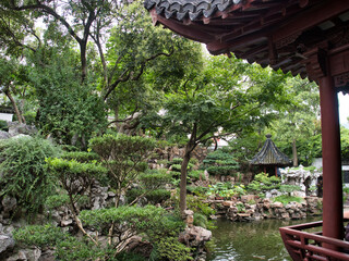 A lush, traditional Chinese garden with a pond, rock formations, and a classic pavilion, offering a...
