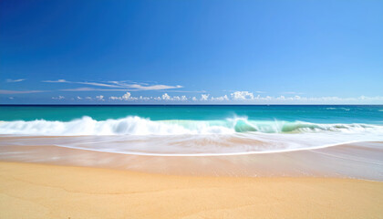 Ocean wave crashing on sandy beach with clear blue sky and distant clouds creating peaceful and refreshing coastal scene under bright sunlight