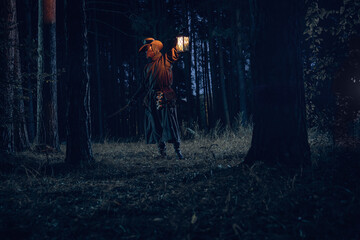 Mysterious figure illuminates dark forest with lantern, evoking fantasy and intrigue.
