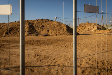 Construction site with sand piles and metal fence under blue sky in Israel