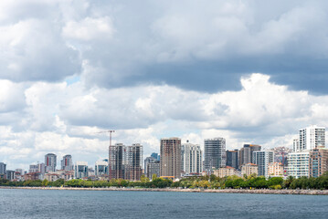 Fototapeta premium Modern city skyline along the waterfront showcasing urban life and natural beauty on a cloudy day