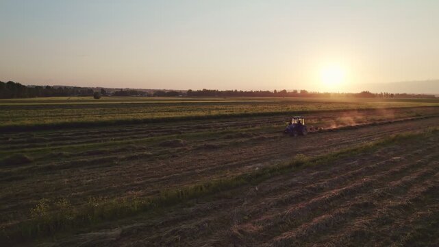 Tractors With Hay Rake And Baler Working In Field At Golden Hour Epic Aerial CInematic. Tedder for tractor. The machine for gathering hay.