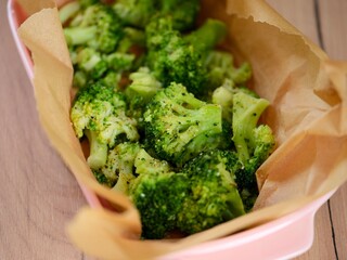 Cooked broccoli in an oven dish with parchment. Close-up