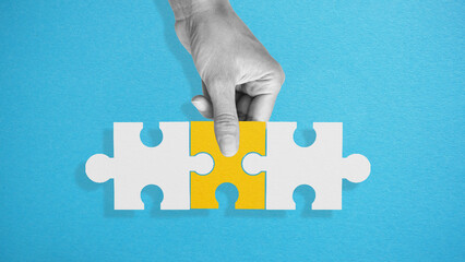 Completing a big job, the final of the project, the successful solution of business problems. The hand puts the last piece of the puzzle