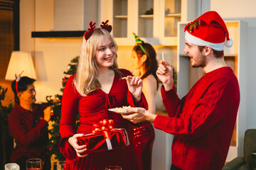 A cheerful group of diverse friends gathers around a decorated Christmas tree, exchanging gifts with laughter and joy at a festive holiday party.