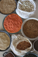 Bowls and bags full of various healthy grains and legumes. Top view.
