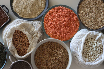 Bowls and bags full of various healthy grains and legumes. Top view.