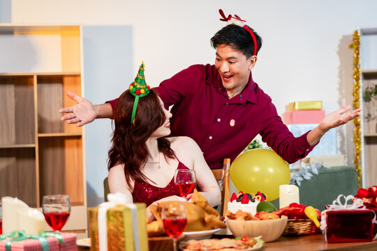 A cheerful group of diverse friends gathers around a decorated Christmas tree, exchanging gifts with laughter and joy at a festive holiday party. - Powered by Adobe