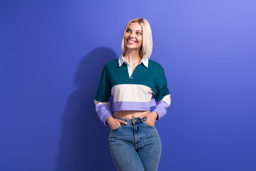 Stylish young blonde woman smiling in casual attire posing against purple background showing casual...