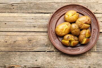 Tasty baked potatoes on wooden table, top view. Space for text