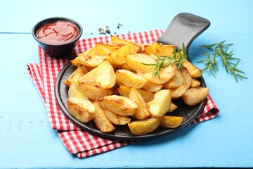Tasty baked potatoes with rosemary and ketchup on light blue wooden table, closeup