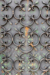 Close-up of a repeating pattern of stylized leaves on a  weathered wrought iron gate, creating an intricate and decorative design in Valença do Minho, Portugal