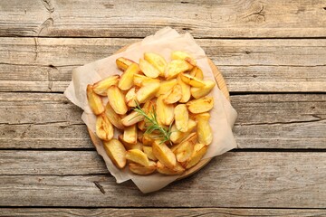 Tasty baked potatoes with rosemary on wooden table, top view