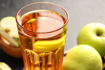 Delicious cider in glass and apples on table, closeup