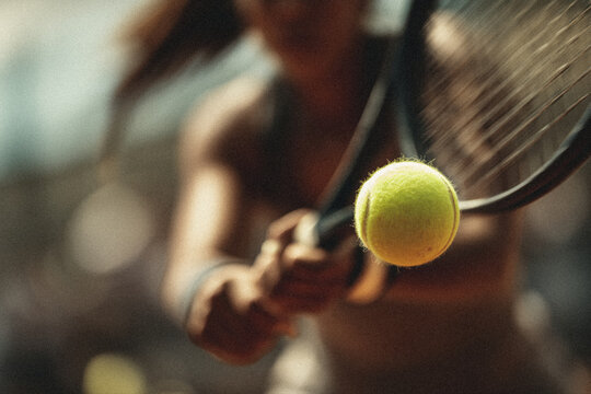 Close-up of tennis ball on motion blur background with female tennis player