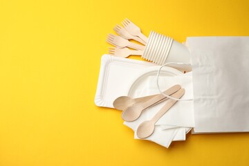 Set of disposable tableware on yellow background, flat lay. Space for text