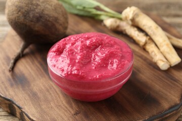 Tasty horseradish sauce with beetroot, roots and vegetable on wooden table, closeup