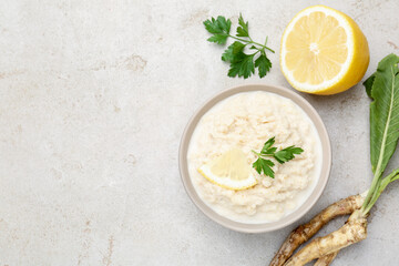 Tasty horseradish sauce with parsley, lemon slice and roots on light table, flat lay. Space for text
