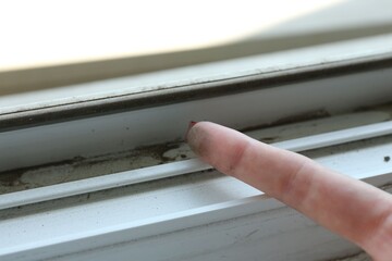 Woman showing dust from window frame indoors, closeup