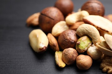 Mix of different nuts on black wooden table, closeup. Space for text