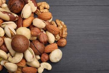 Mix of different nuts on black wooden table, flat lay. Space for text