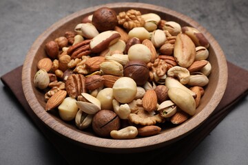 Mix of different nuts in bowl on grey table, closeup