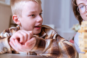 Fototapeta premium A mother and her son with hearing aids share a joyful moment playing board games together. A heartwarming scene of inclusive family bonding, love, and adaptive play