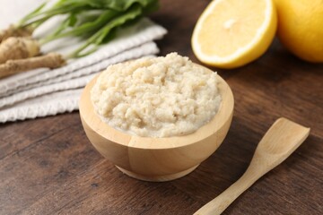 Tasty horseradish sauce and roots on wooden table, closeup