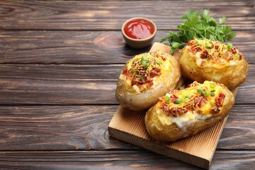 Tasty stuffed baked potatoes served on wooden table, closeup. Space for text