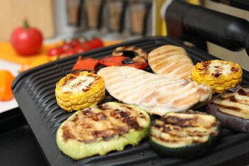 Electric grill with tasty meat and vegetables in kitchen, closeup