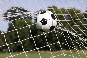 Hitting soccer ball in net outdoors, closeup. Football game