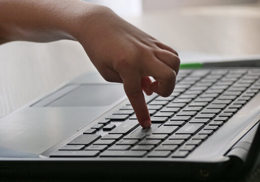 Close-Up of a Child's Finger Pressing an Enter Key on a Laptop Keyboard