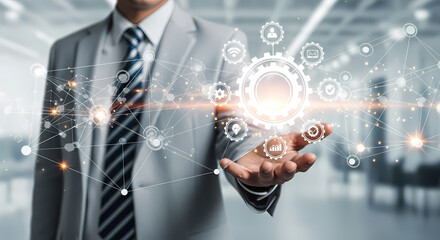 Businessman holding a glowing digital interface with a central gear, symbolizing technology, automation, and innovation.