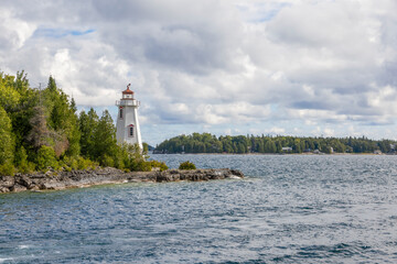 Charming view of Big Tub Harbour Lighthouse in Tobermory, Ontario, featuring serene waters and lush greenery.