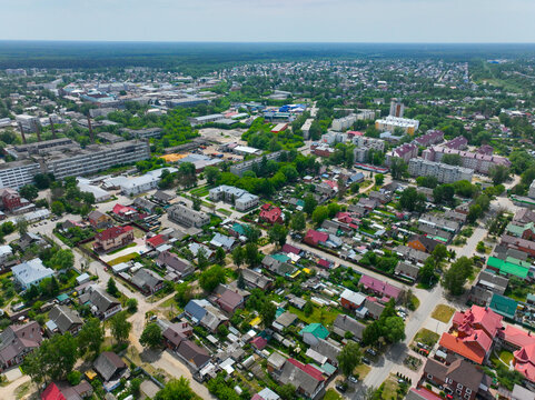 A wide aerial view of the urban landscape of Gus Khrustalny, showing its mix of industrial buildings and residential areas with a clear blue sky.