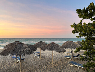 Beach with a view of the ocean. Sunset. On the beach stood sunbeds under the canopies. On the right leaves from wood