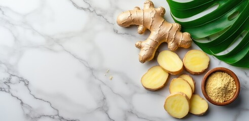 Fresh ginger root slices and whole ginger on marble with green leaf