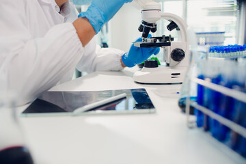 medical or scientific researcher researching and experimenting Multi-colored solution, vial and microscope In the laboratory or in the laboratory by wearing blue gloves and white clothing completely.