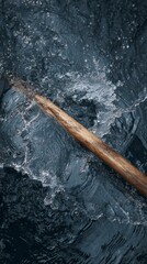 Wooden oar splashing dark water
