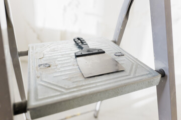 Ladder with a paint scraper resting on the step for home improvement tasks