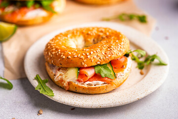 Healthy breakfast food. Bagel sandwich with salmon, cream cheese, cucumber and microgreens on white background. Burger with salmon.