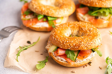 Healthy breakfast food. Bagel sandwich with salmon, cream cheese, cucumber and microgreens on white background. Burger with salmon.