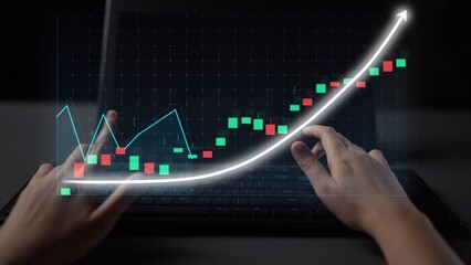 Close-up view of hands interacting with a laptop displaying a digital graph and stock data, highlighting financial growth and data analytics concepts in a modern workspace. Copula